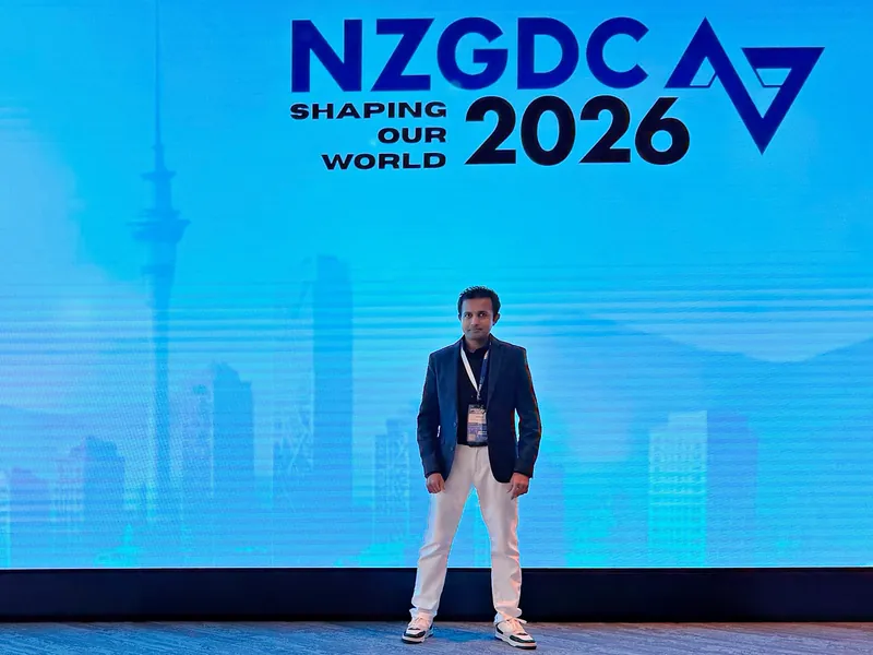 Dr. Yasas Sri Wickramasinghe in front of the NZGDC 2026 Shaping Our World backdrop