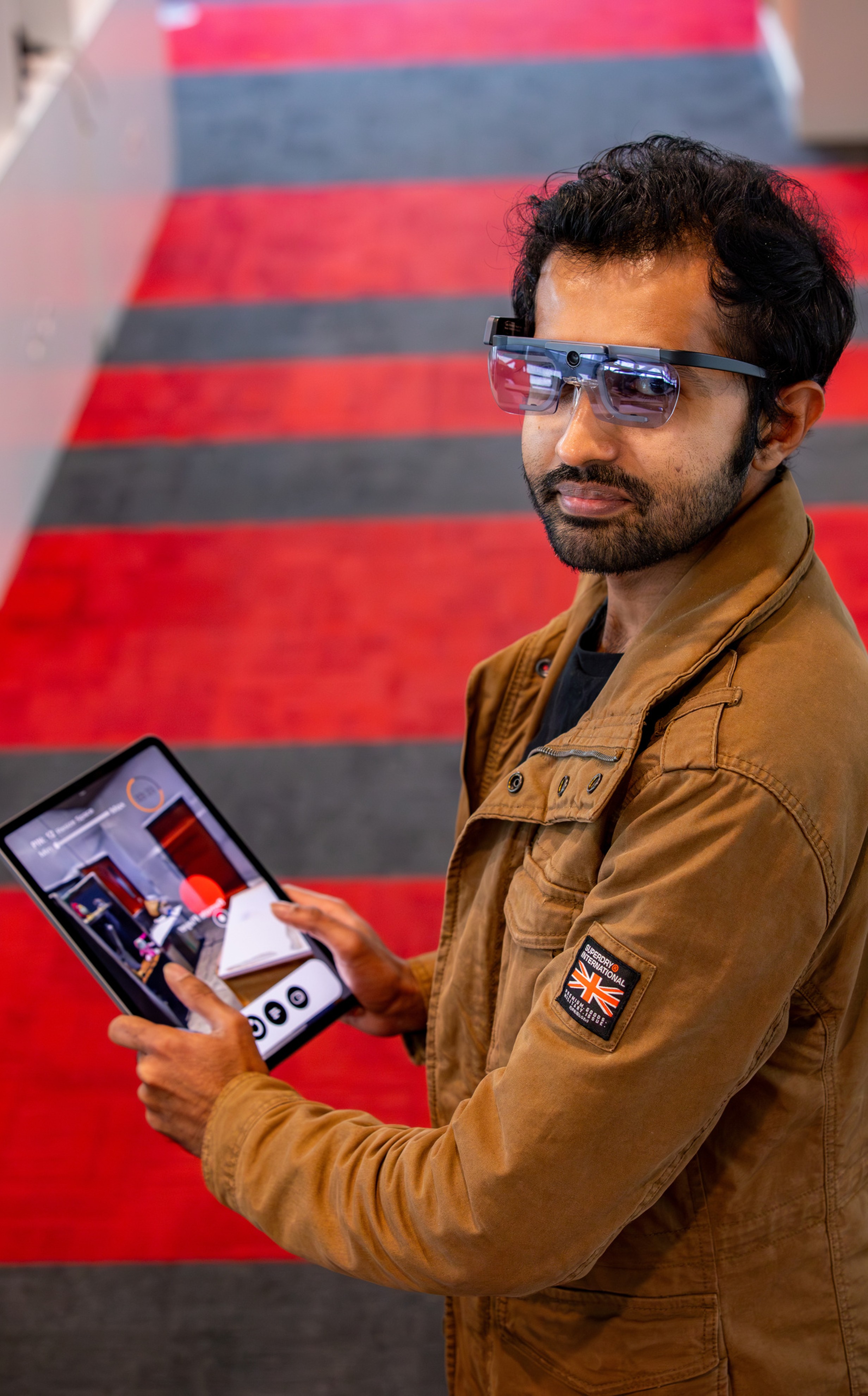 Dr. Yasas Sri Wickramasinghe wearing AR eye-tracking glasses and reviewing a location-based AR scene on a tablet
